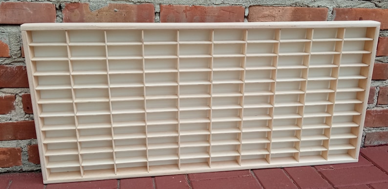 May include: A wooden display case with 72 individual compartments for storing small items. The case is made of light wood and has a natural finish.