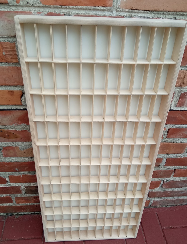 May include: A wooden display case with a grid of small compartments. The case is made of light wood and has a natural finish.