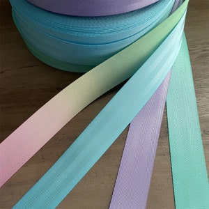 May include: Four rolls of pastel colored webbing with a subtle textured pattern. The colors are light pink, light blue, lavender, and light green.