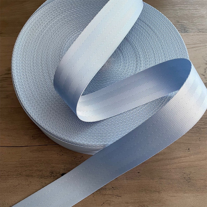 May include: A roll of light blue webbing with a textured surface. The webbing is approximately 1 inch wide.