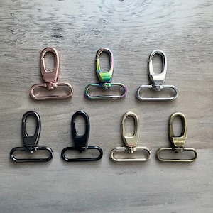 May include: Set of eight metal swivel clasps in various finishes, including rose gold, iridescent, silver, black, gold, and antique brass. Each clasp features a D-ring and a hook.
