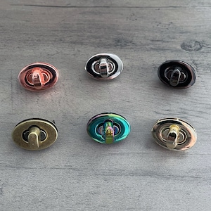 May include: Six oval-shaped metal clasps in different finishes: rose gold, silver, black, iridescent, brass, and gold.