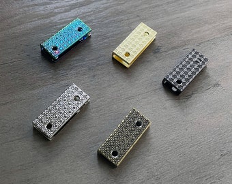 May include: Five metal rectangular buckles with a decorative pattern. The buckles are in different colors: silver, gold, black, and iridescent.