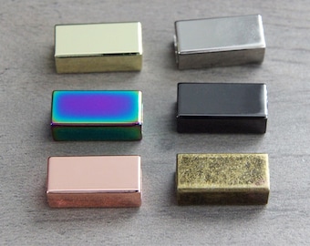 May include: Six different colored metal slider buckles. The buckles are rectangular and have a smooth finish. The colors are gold, silver, rainbow, black, rose gold, and antique brass.