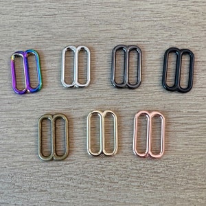 May include: Set of ten metal slider buckles in various colors, including rainbow, silver, black, gunmetal, brass, green, and rose gold.