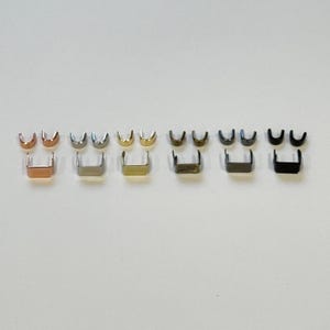 Può includere: Otto set di tiretti per cerniera in metallo in diverse finiture: oro rosa, argento, oro, canna di fucile, nichel, nichel nero e nero. Ogni set include due tiretti per cerniera.