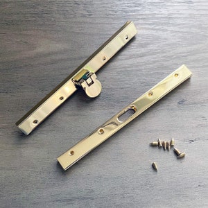 May include: Two gold metal purse frame pieces with a gold metal clasp and eight gold screws.