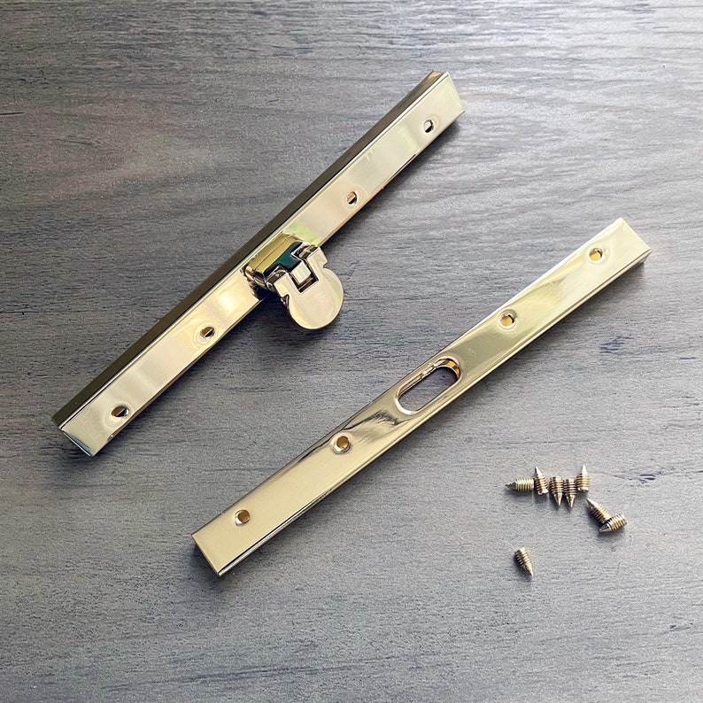 May include: Two gold metal purse frame pieces with a gold metal clasp and eight gold screws.