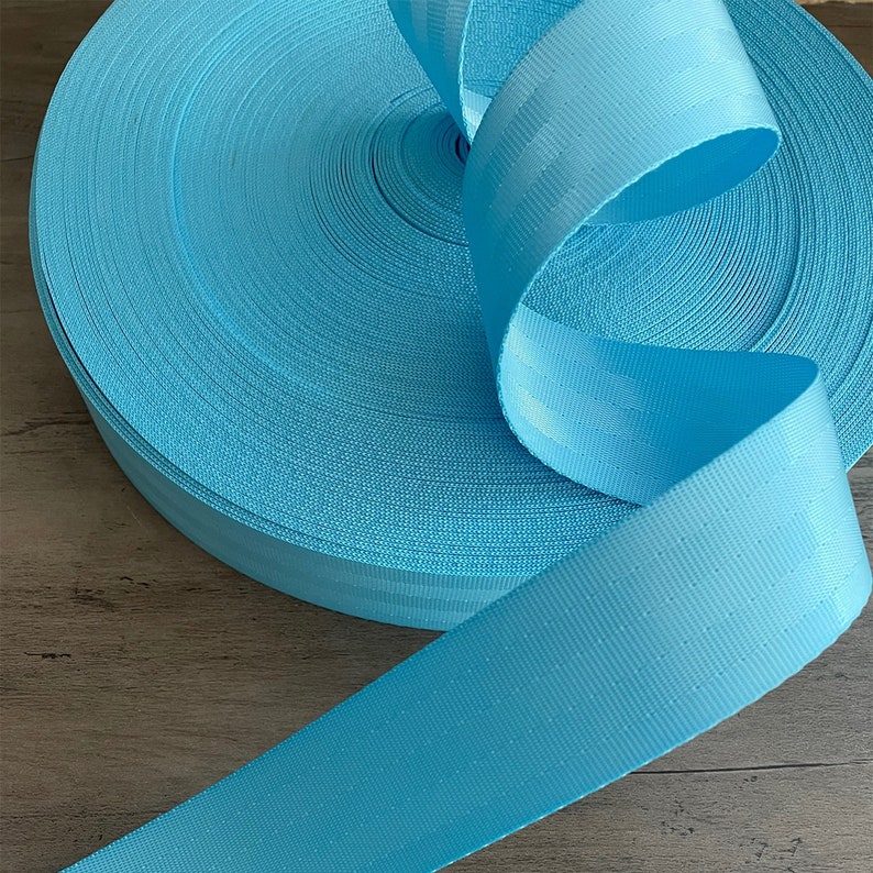 May include: A roll of light blue webbing, a type of strong, woven fabric often used for straps and belts.