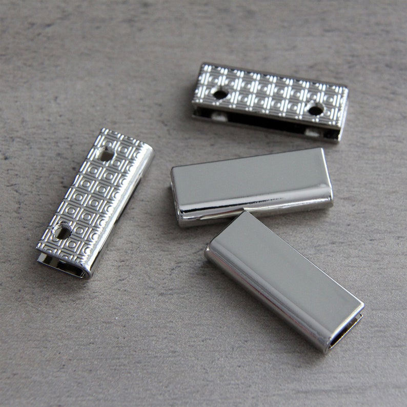 May include: Four silver metal slider buckles with a geometric pattern. The buckles are rectangular and have two holes on each side.