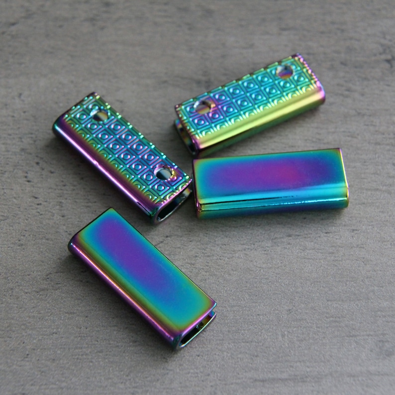 May include: Four iridescent metal slider buckles. The buckles are rectangular and have a textured surface. They are a mix of blue, green, purple, and gold.