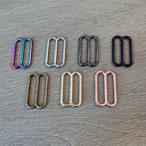 May include: Seven metal slider buckles in different finishes: rainbow, silver, gunmetal, black, antique brass, gold, and rose gold.