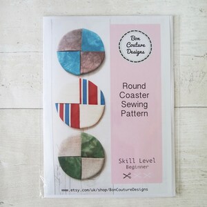 Puede incluir: Un patrón de costura para un posavasos redondo. El patrón presenta tres diseños diferentes con un esquema de color azul, rojo y verde. El patrón está etiquetado como "Round Coaster Sewing Pattern" y "Skill Level Beginner".