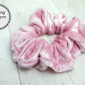 Pode incluir: Um elástico de cabelo de veludo rosa. O scrunchie é feito de veludo macio e felpudo e é perfeito para adicionar um toque de elegância a qualquer penteado.