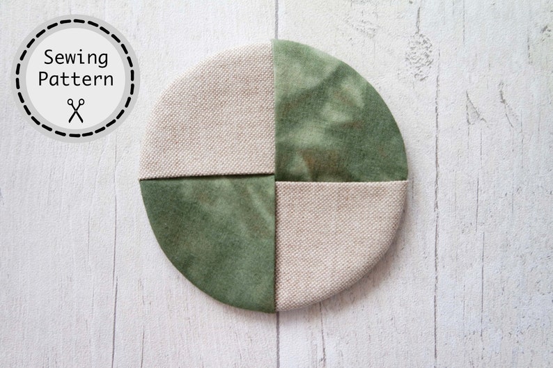 Pu&ograve; includere: Un sottobicchiere rotondo in tessuto verde e beige con un design a patchwork. Il sottobicchiere &egrave; composto da quattro quadrati di tessuto, due verdi e due beige. Il tessuto verde ha un motivo tie-dye.