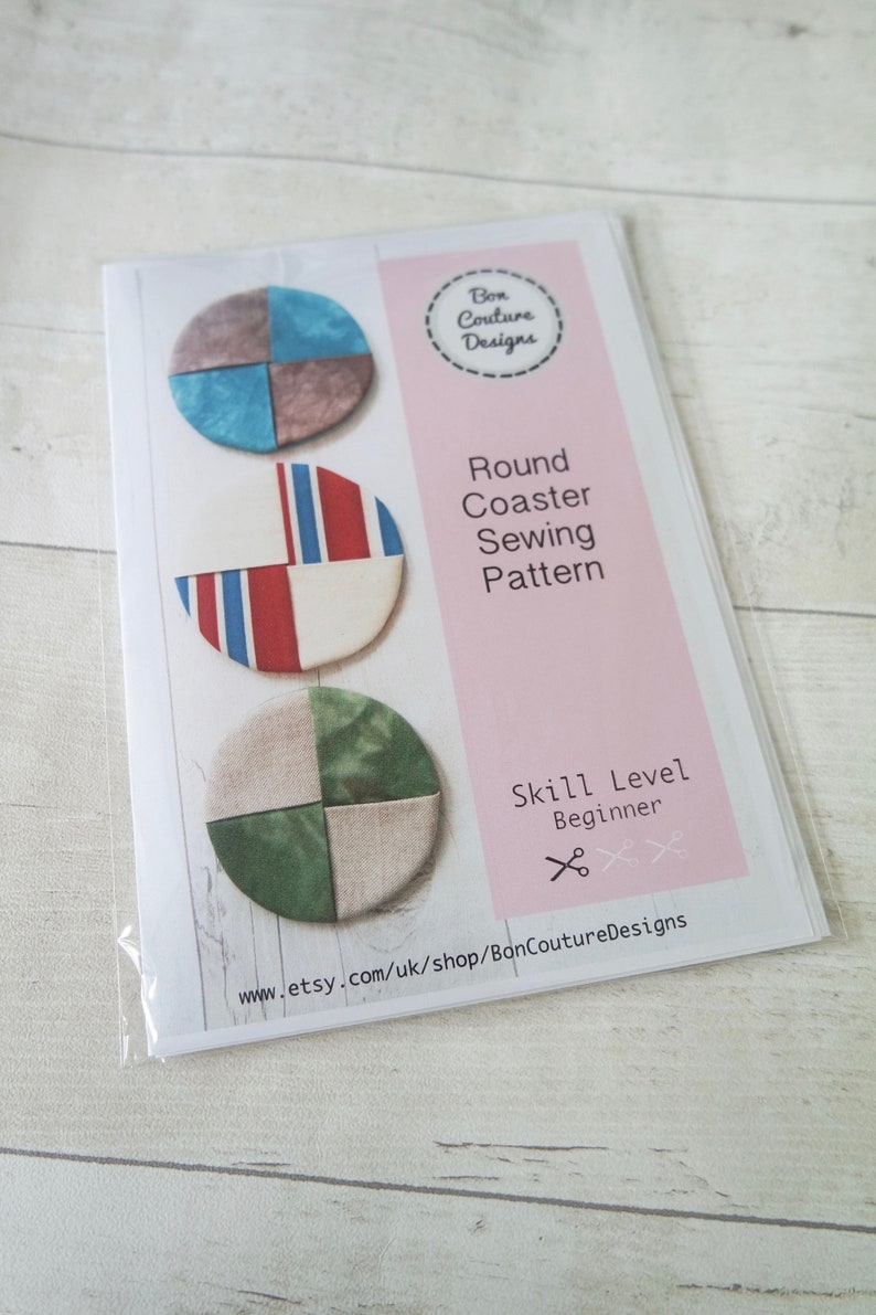 Pu&ograve; includere: Un modello di cucito per realizzare sottobicchieri rotondi in tessuto. Il modello include tre diversi design, ognuno con un diverso schema di colori. Il modello &egrave; etichettato "Round Coaster Sewing Pattern" e "Skill Level: Beginner".