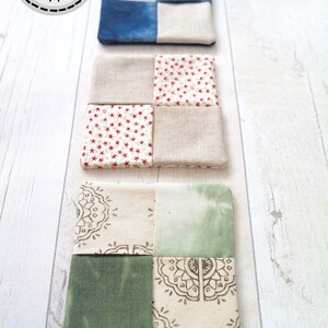 May include: Three fabric coasters with a patchwork design. The top coaster is blue and white, the middle coaster is red, white, and beige, and the bottom coaster is green, white, and beige.