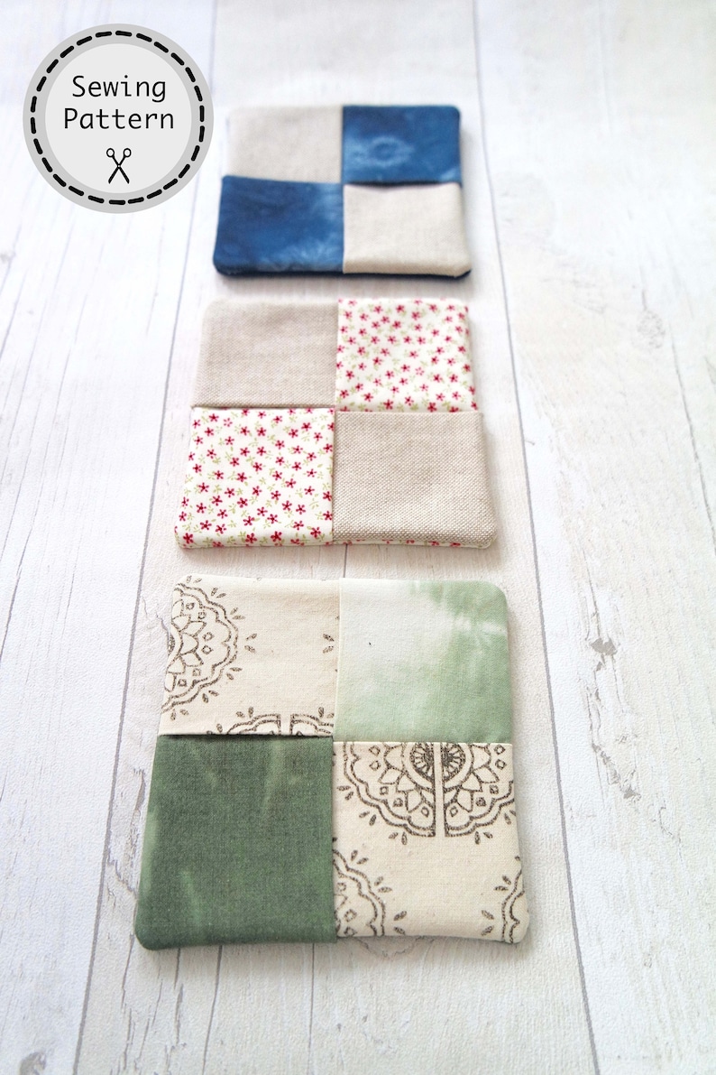 May include: Three fabric coasters with a patchwork design. The top coaster is blue and white, the middle coaster is red, white, and beige, and the bottom coaster is green, white, and beige.