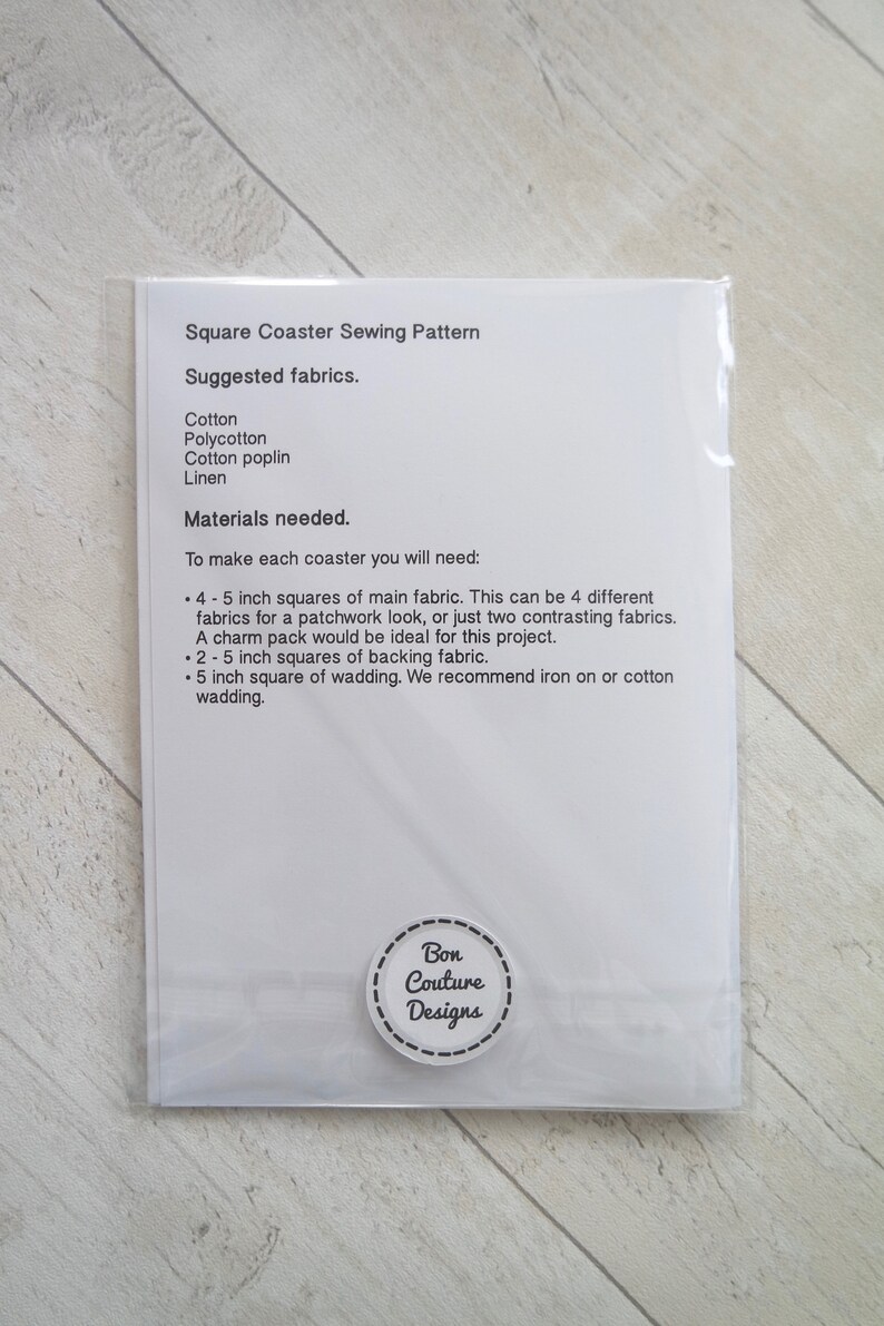 May include: A white sheet of paper with instructions for making a square coaster. The instructions include a list of materials needed, such as cotton fabric, backing fabric, and wadding. The paper also includes the text "Square Coaster Sewing Pattern" and "Bon Couture Designs".
