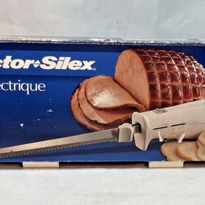 May include: Proctor Silex Easy Slice electric knife in its original box. The box features an image of sliced ham and vegetables. The knife has a white handle and a stainless steel blade.