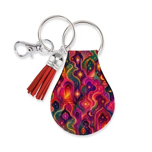 May include: A teardrop-shaped keychain featuring a vibrant, intricate pattern of glowing arches, staircases, and hanging lanterns in shades of magenta, orange, purple, and teal. The keychain includes a silver metal ring, a clasp, and a red leather tassel.
