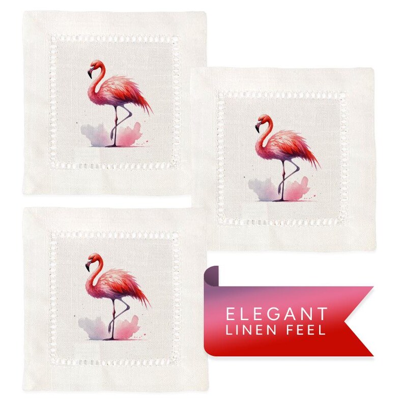 May include: Set of three white linen cocktail napkins with pink flamingo illustrations. Each napkin features a pink flamingo standing on one leg in a watercolor style. The napkins have a delicate white embroidered border.