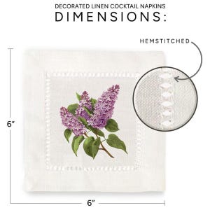 May include: White linen cocktail napkin with a hemstitched edge. The napkin features a floral design of purple lilacs on a white background. The napkin measures 6 inches by 6 inches.
