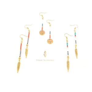 May include: Three pairs of gold dangle earrings with colorful beads and a gold feather charm. The earrings feature a bull head charm on a gold disc.