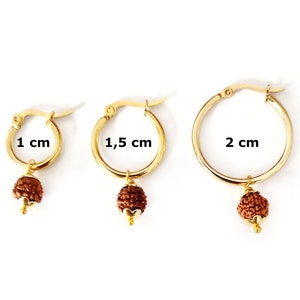 May include: Three gold hoop earrings with a brown bead charm. The hoops are 1 cm, 1.5 cm, and 2 cm in diameter.