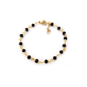 May include: A delicate bracelet featuring small, faceted black beads strung on gold-colored wire. The bracelet has a gold-colored clasp and is displayed against a white background. The jewelry is suitable for everyday wear or special occasions.