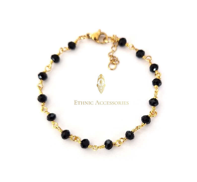 May include: A gold-toned bracelet featuring black faceted beads strung on a delicate wire. The bracelet has a lobster clasp closure and an adjustable chain. The text "Ethnic Accessories" is printed on the image.