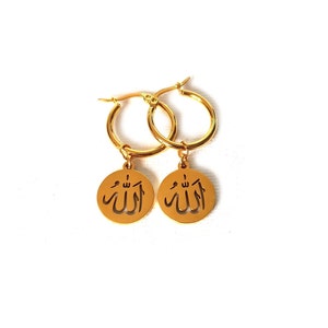 May include: Gold hoop earrings with a dangling charm featuring the Arabic word "Allah" in a cut-out design.