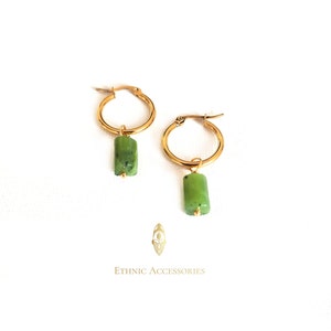 May include: Gold hoop earrings with a green stone pendant. The earrings are simple and elegant, perfect for everyday wear.