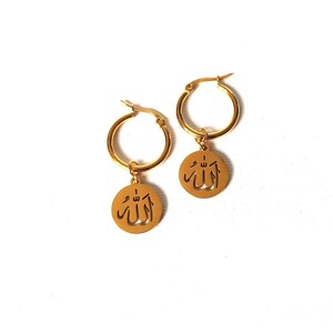 May include: Gold hoop earrings with a dangling charm featuring the Arabic word "Allah" in a cut-out design.