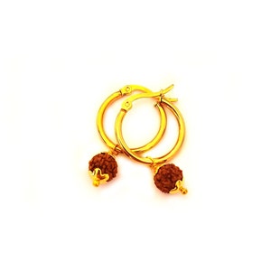 May include: Gold hoop earrings with small brown beads hanging from them.