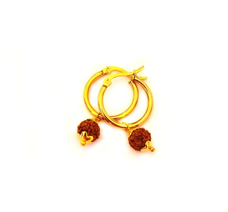 May include: Gold hoop earrings with small brown beads hanging from them.