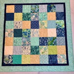 May include: A blue and green patchwork quilt with a variety of sea-themed patterns, including seashells, starfish, and seaweed.