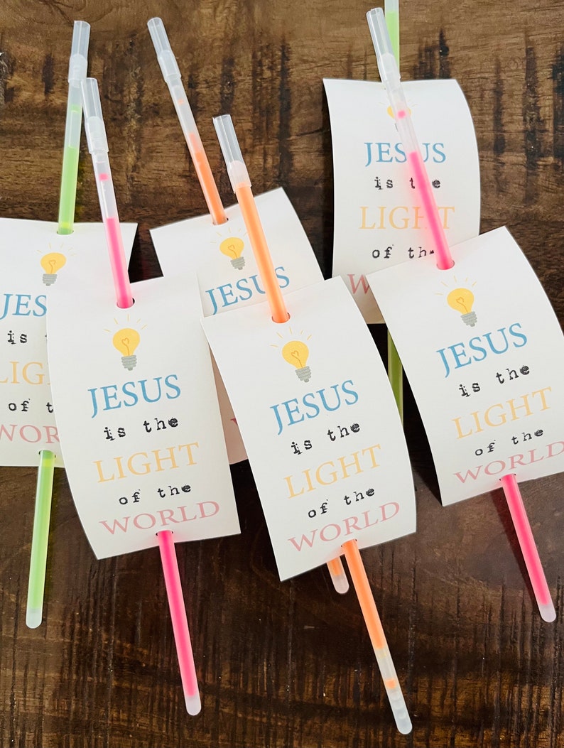 May include: Five glow sticks with white paper tags attached. The tags have a lightbulb graphic and the text "JESUS is the LIGHT of the WORLD".