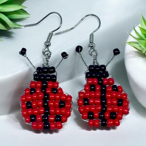 May include: A pair of red and black ladybug earrings made with small beads and wire. The earrings have a simple hook fastening.