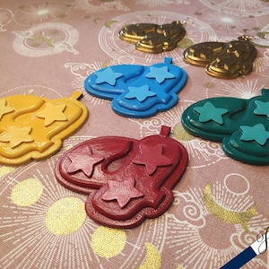 Può includere: Quattro paia di orecchini a forma di stella di diversi colori: blu, giallo, verde e rosso. Ogni orecchino ha tre stelle.