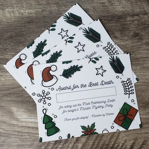 以下が含まれることがあります： 緑と茶色のクリスマスをテーマにしたデザインの白いカード。カードには「Award for the Best Death: for acting out the Most Entertaining Death for tonight's Murder Mystery Party. Thank you for playing! - Murders by Chelsea」と書かれています