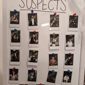 May include: A white board with the word "SUSPECTS" written in black marker. There are 16 Polaroid photos pinned to the board, each featuring a different person.