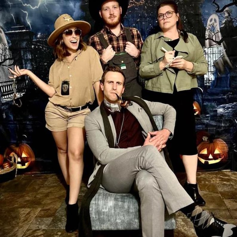 May include: Four people dressed in costumes for a Halloween party. A woman in a brown uniform and a hat with a badge, a man in a plaid shirt and overalls, a woman in a green jacket and a man in a gray suit with a pipe.