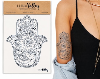 May include: A Luna Valley temporary tattoo sheet featuring a black hamsa hand design with intricate floral and paisley patterns. The packaging includes the text LUNA VALLEY TEMPORARY TATTOOS, LASTS UP TO 5 DAYS, SKIN SAFE & NON TOXIC, and WATERPROOF.