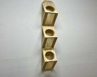 May include: A wooden wall-mounted shelf with four circular openings. The shelf is made of light-coloured wood and has a simple design.
