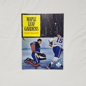 May include: A vintage magazine cover featuring two hockey players in blue and white uniforms on the ice. The magazine is titled "Maple Leaf Gardens Hockey Magazine" and costs 75 pence.