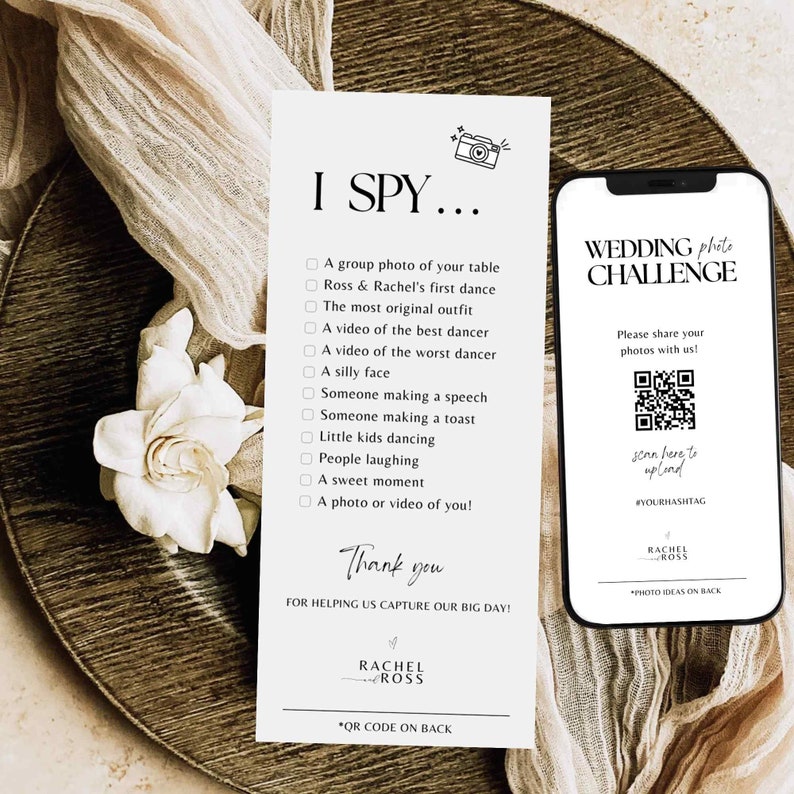 Puede incluir: Una tarjeta blanca con el texto "I Spy..." y una lista de elementos para encontrar en una boda. La tarjeta tambi&eacute;n incluye el texto "&iexcl;Gracias por ayudarnos a capturar nuestro gran d&iacute;a!" y los nombres "Rachel & Ross". Un tel&eacute;fono blanco con una pantalla negra que muestra un c&oacute;digo QR y el texto "Wedding Photo Challenge" se muestra en el lado derecho de la tarjeta.