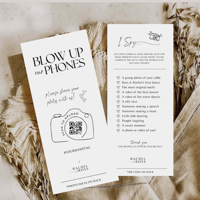 May include: Two white cards with black text and illustrations. The first card says "Blow Up Our Phones" and has a camera with a QR code. The second card says "I Spy..." and has a list of things to find in photos, such as "A group photo of your table" and "Ross & Rachel's first dance".
