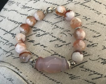 May include: A pink agate bracelet with silver beads and a large pink agate charm. The bracelet is made of natural stones and is a beautiful piece of jewelry.