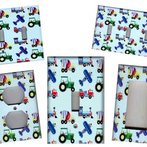 May include: A set of light blue light switch and outlet covers with a pattern of colorful toy trucks, airplanes, and cement mixers.